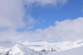 clouds over snow-capped mountains on a sunny day