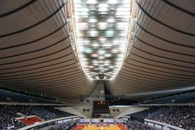 Basketball court with players and spectators, in lights