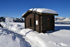 Beautiful landscape with the wooden hut among the snow in sunlight and shadows, in France, under the blue sky