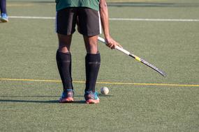 Player playing hockey on the field, in light