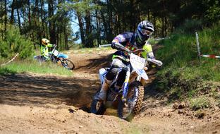 Motocross riders in colorful equipment, on the path, among the plants