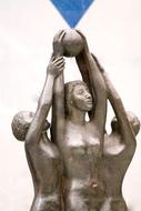 Shiny statues of the women with ball, under the blue sky