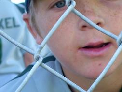 Portrait of the baseball player behind the metal fence