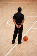 referee with the ball on the basketball court