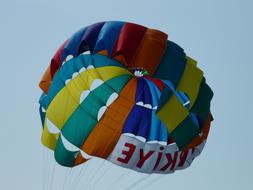 Colorful parachute with the sign, in the blue sky