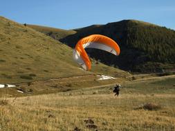 Person with the colorful parachute, on the beautiful and colorful mountains, under the blue sky