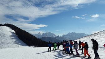 People skiing on the beautiful, snowy mountains in sunlight, under the blue sky with white clouds