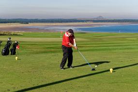 a man hits the ball on a green golf course