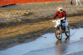 boy riding Motorcycle on beach at water