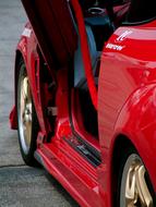 Shiny, red racing car with open doors, on the road