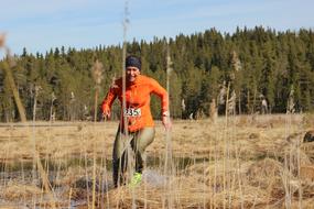 Woman, running among the colorful plants in sunlight, in the winter