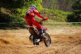 motorcycle racer in red uniform racing on the sand