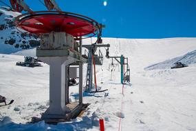 Ski lift on the beautiful, snowy mountain in sunlight, under the blue sky