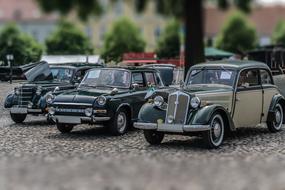 Figures of the beautiful, retro cars, near the green trees