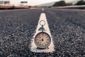 vintage alarm Clock on asphalt road