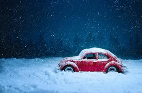 Beautiful, red, retro car in white snow, in moonlight, near the trees, at night