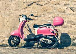 pink vintage scooter against a stone wall