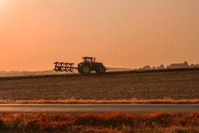 landscape of Tractor on Fields at sunset