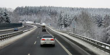 Traffic on road through forest at winter