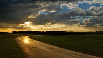 landscape of sunset and dark clouds over road