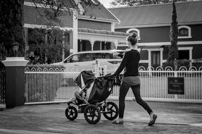 Black and White photo of woman and Baby Carriage on Road