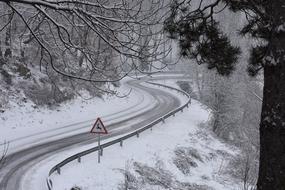 Beautiful, snowy road with the red, white and black deer sign, among the forest in Nevada, America