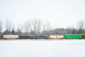 Beautiful landscape with the colorful train on the tracks, among the white snow and trees