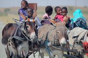 black children ride donkeys in Africa