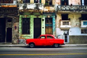 red retro car parked near an old building in Havana, Cuba