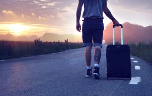 a man with a suitcase on the road during sunset