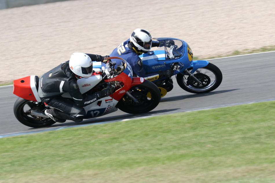 People, riding on the colorful motorbikes, on the road, near the green grass, in Castle Donigton, England