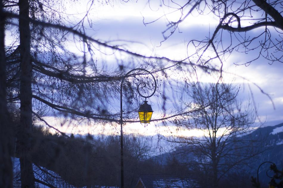 yellow street lamp in the background of snowy mountains in the village of Montalbert