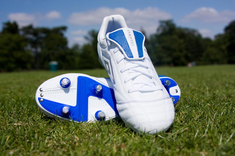 Blue and white 'Umbro' football boots on the green grass, among the green trees