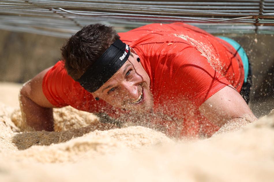 Man, doing steeplechase, on the sand in the cross country