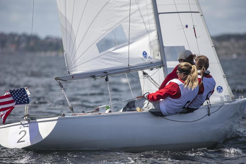Women, sailing on the sailboat with the flag of USA, on the water