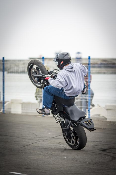 boy riding motorbike on one wheel
