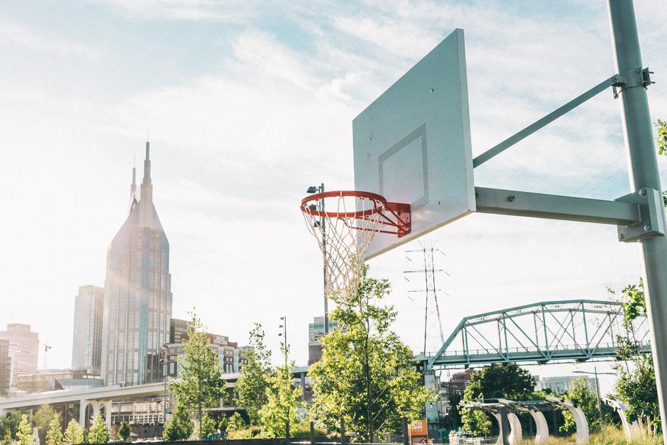 photo of a basketball hoop on the background of a railway bridge