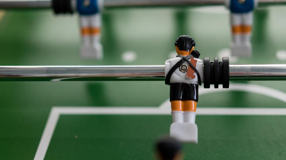 Player figures on the green and white field of the tabletop soccer