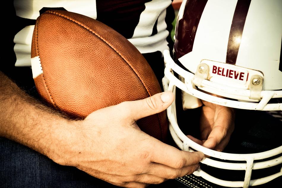 Person, holding American football ball and helmet