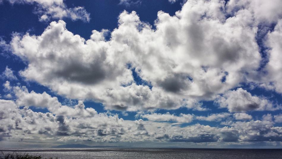 Beautiful, blue sky with clouds, above the shiny water with light