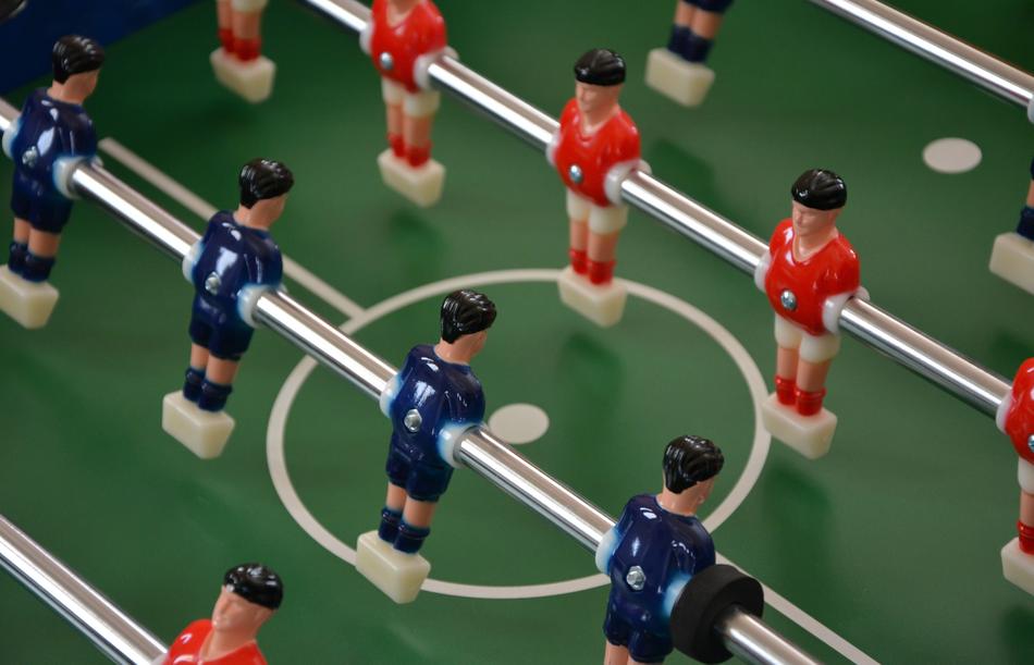 Blue and red player figures, on the table soccer with green and white field