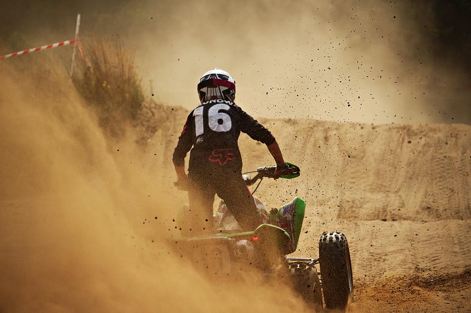 Back view of the rider on the quad, in the sand, on the landscape