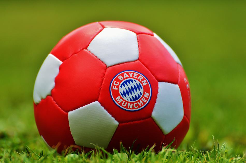 Close-up of the red, white and blue football ball with the logo of 'Bayern Munich' on the green grass of Allianz Arena