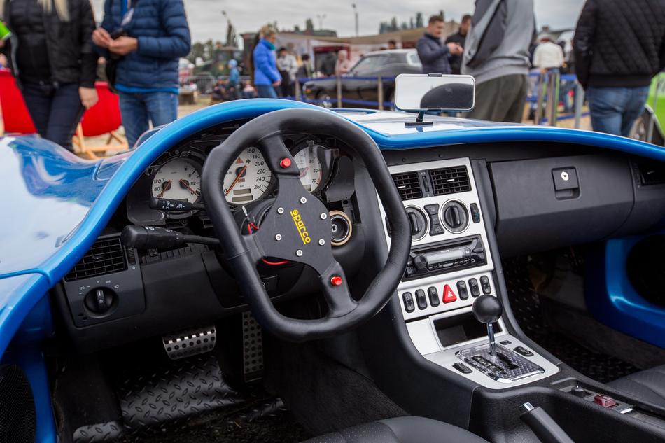 Interior of the blue, shiny sports car, with the dashboard, among the people