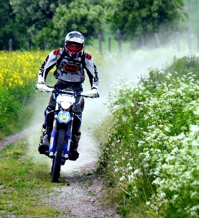 Motorcyclist, riding on the path, among the colorful plants, with the smoke