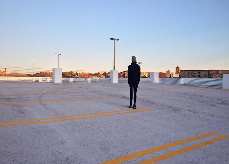 Runner standing on rooftop parking in city