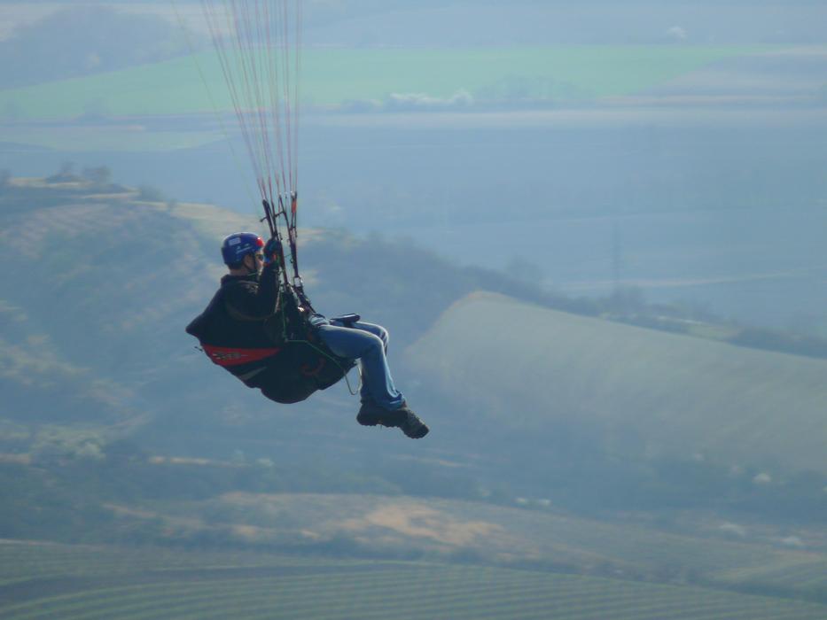 skydiver over fields in haze