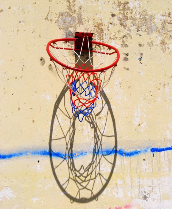 Close-up of the red basket hoop with shadow on the wall, in sunlight