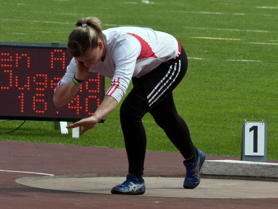 Woman at the shot put competition, near the green grass