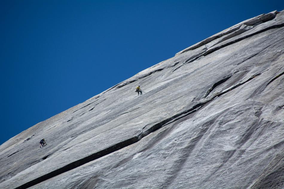 Person doing rock climbing on the mountain in Yosemite, California, at blue sky on background